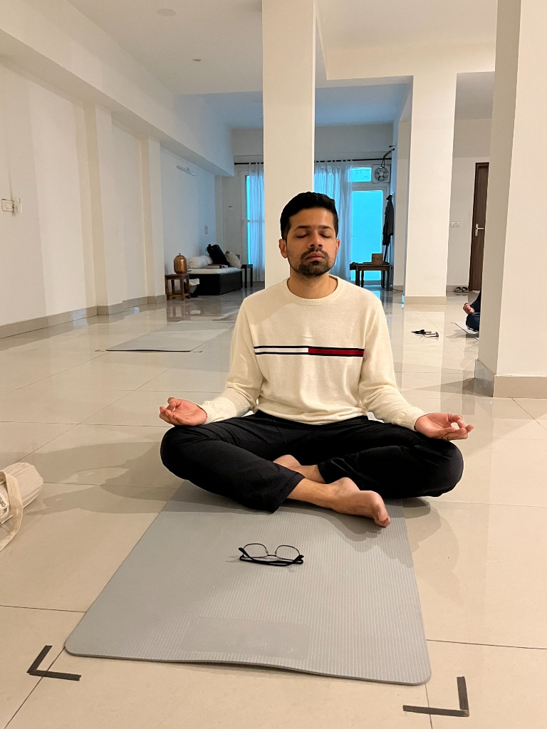 Young man sitting cross-legged in silent meditative stillness in Sonepat yoga studio