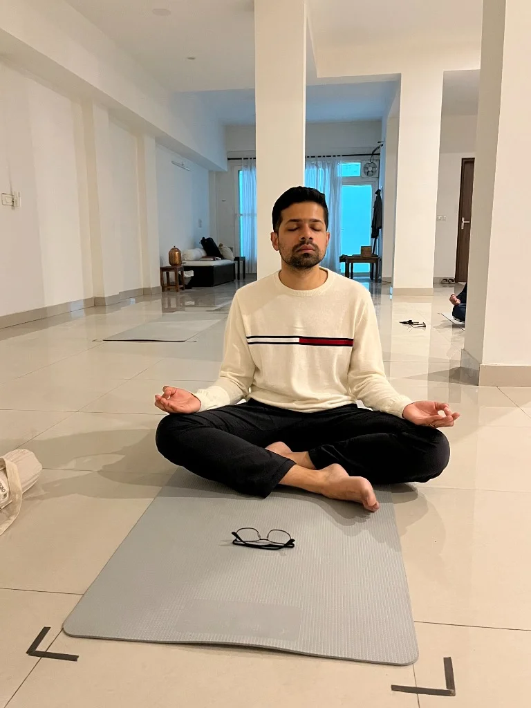 Young man sitting cross-legged in silent meditative stillness in Sonepat yoga studio