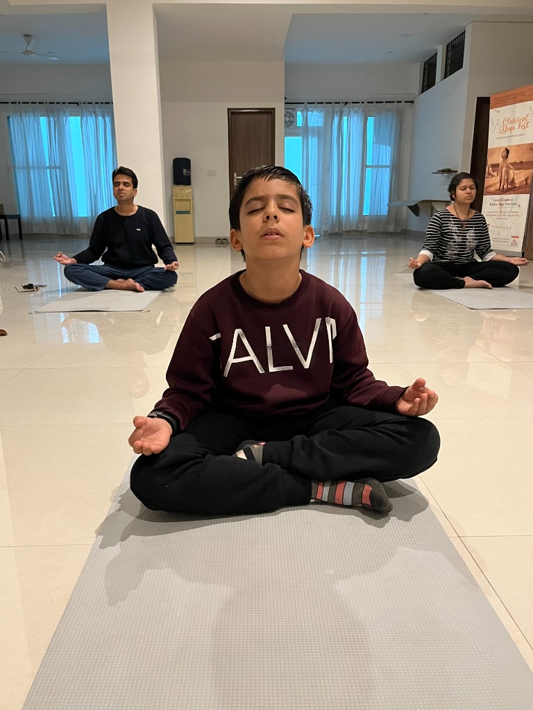 Young boy with eyes closed meditating peacefully alongside family in studio