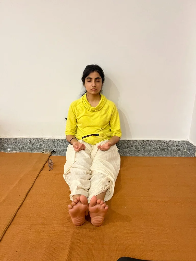 Young woman in seated yoga posture focusing inward on ochre practice mat